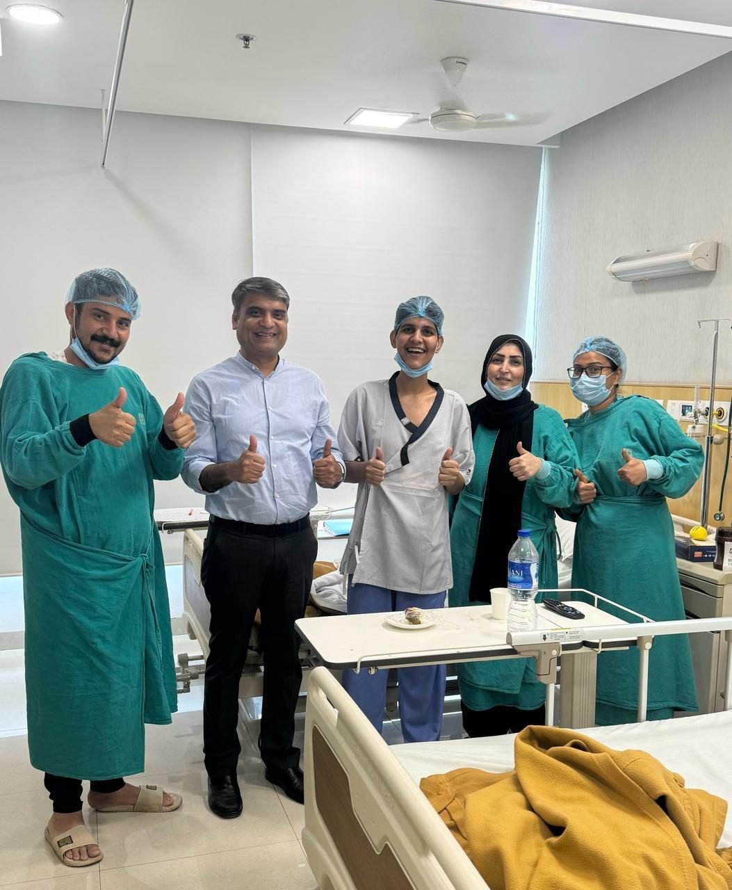Young patient giving thumbs up with family and surgical team